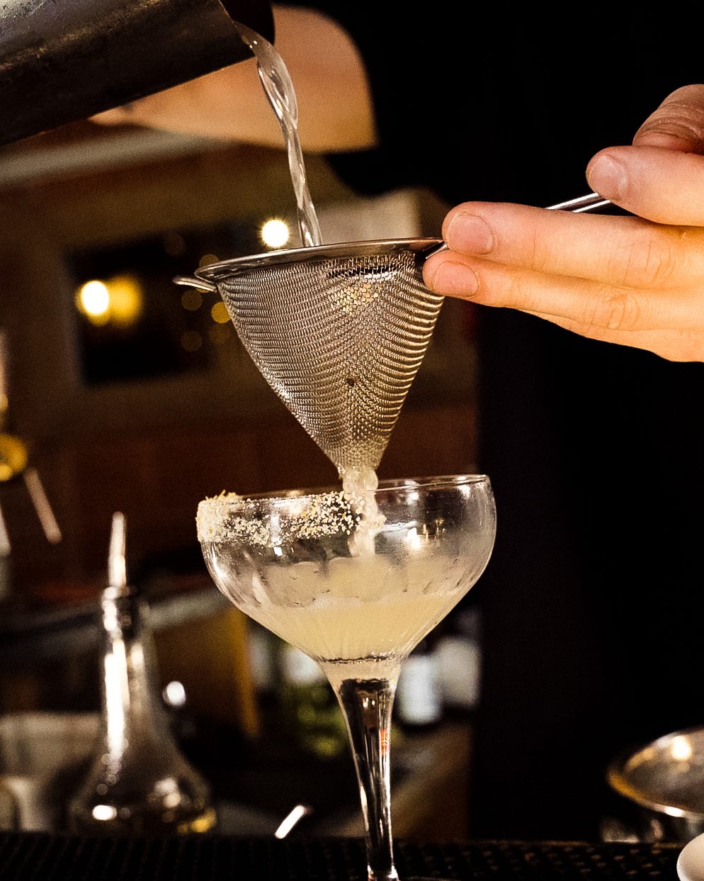 Cocktail filtré à la passoire fine derrière le comptoir de L'Arrosoir à Toulouse